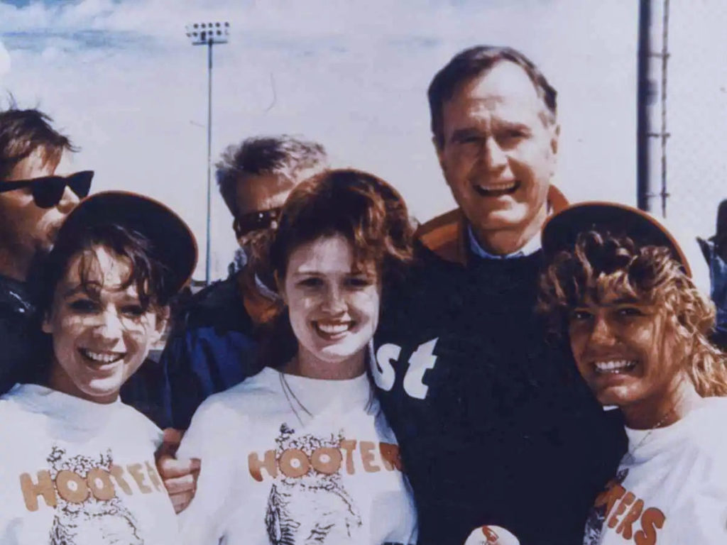 President George H.W. Bush op de foto met Hooter girls